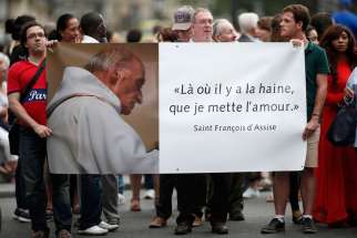 People hold a banner with a picture of French priest Father Jacques Hamel, which reads, &quot;Where there is hatred, let me sow love,&quot; after a July 27 Mass at the Notre Dame Cathedral in Paris. Father Jacques Hamel was killed in a July 26 attack on a church at Saint-Etienne-du-Rouvray near Rouen by assailants linked to Islamic State groups.