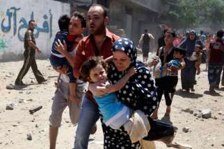 Palestinians run following what police said was an Israeli airstrike on a house in Gaza City July 9. The Israeli army intensified its offensive on the Hamas-run Gaza Strip, striking Hamas sites and killing dozens of people in a military operation it says is aimed at quelling rocket fire against Israel.