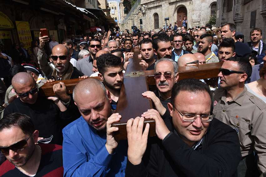 Mousa Kamar, front right, and his son, Youssef, far left corner, carry the large wooden cross during the Good Friday procession on the Via Dolorosa in Jerusalem&#039;s Old City March 25, 2016. Mousa Kamar and his sons are carrying on the tradition of his grandfather and father, carrying the cross on Good Friday.