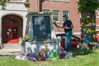 A man places flowers on a memorial in front of the former Kamloops Indian Residential School in B.C. May 29. 