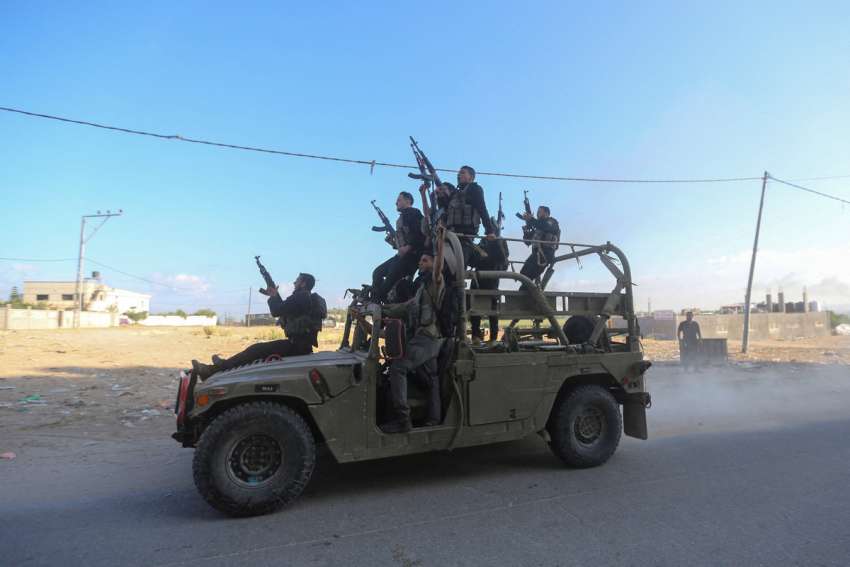 Palestinian militants ride an Israeli military vehicle that was seized by gunmen who infiltrated areas of southern Israel, in the northern Gaza Strip Oct. 7, 2023.