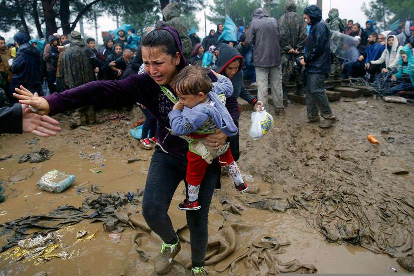 A Syrian refugee woman cries as she carries her baby through the mud to cross the border from Greece into Macedonia near the Greek village of Idomeni Sept. 10. Canadian Church leaders and organizations are demanding a stronger Canadian response to the refugee crisis.