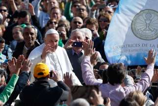 Pope Francis passes a banner referring to eucharistic adoration as he arrives to lead his general audience in St. Peter&#039;s Square at the Vatican March 18.