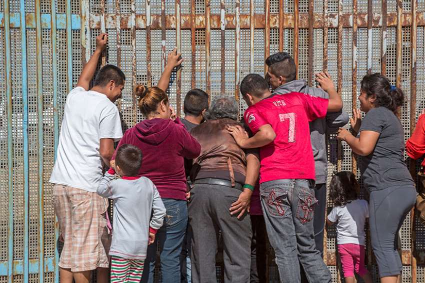  Family members in Tijuana, Mexico, separated by deportation, visit through the U.S.-Mexico border fence Oct. 16, 2016. U.S. bishops have varying opinions on providing sanctuary.