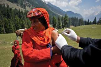 A health care worker administers a COVID vaccine to a shepherd near Lidderwat, India.