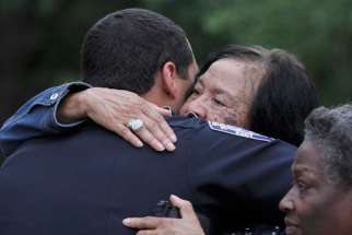 A police officer is embraced after a July 17 vigil at St. John the Baptist Church in Zachary, La., for the fatal attack on policemen in Baton Rouge, La. A former Marine dressed in black shot and killed three Baton Rouge law enforcement officers that day, less than two weeks after a black man was fatally shot by police here in a confrontation that sparked nightly protests nationwide.