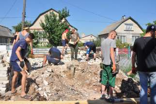Volunteers from Lviv, Ukraine, clear debris to repair sewer and septic tank lines Aug. 5 in eastern Ukraine. The home was destroyed by three mortar shells during the war.
