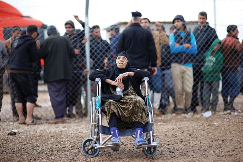 An elderly woman from Mosul, Iraq, sits at a refugee camp in Khazer, Iraq. Refugee advocates are demanding the federal government clear the refugee backlog.