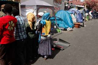 African refugees wait to receive clothing near tents where they dwell temporarily on a street in Rome July 14. A papal think tank is convening to tackle the global refugee crisis.