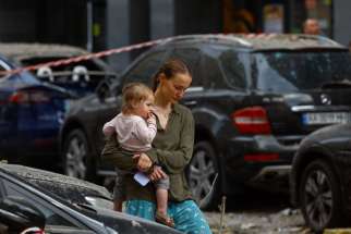 A local woman carries a baby at the site where an apartment building was damaged during Russian missile strikes in Kyiv, Ukraine June 24, 2023.
