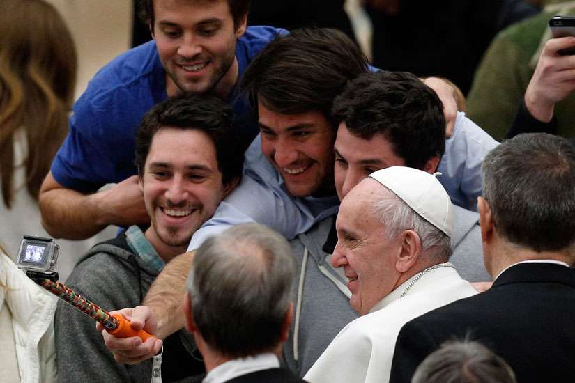 Young men take a selfie with Pope Francis as he leaves his general audience in Paul VI hall at the Vatican Jan. 20.