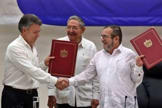 Colombian President Juan Manuel, left, shakes hands with FARC delegate Londono Echeverri &#039;Timochenko&#039; in Havana Juen 23 as Cuban President Raul Castro looks on. The Colombian government and rebel group signed a bilateral ceasefire agreement in Cuba.