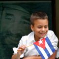 A boy holds a Cuban flag with a portrait of Fidel Castro behind him as he watches Pope Benedict XVI&#039;s caravan make its way to the airport in Havana March 28.