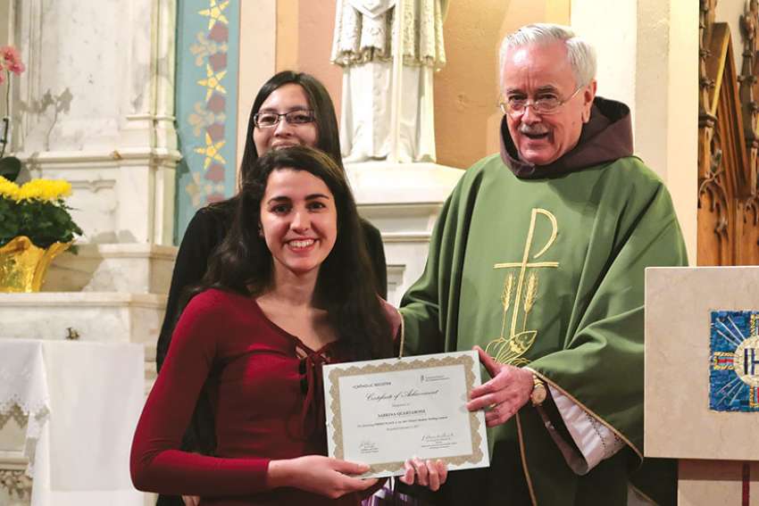 Sabrina Quartarone accepts her third-place certificate from Fr. Damian MacPherson during a presentation Mass Feb. 5 at St. Cecilia’s Church.