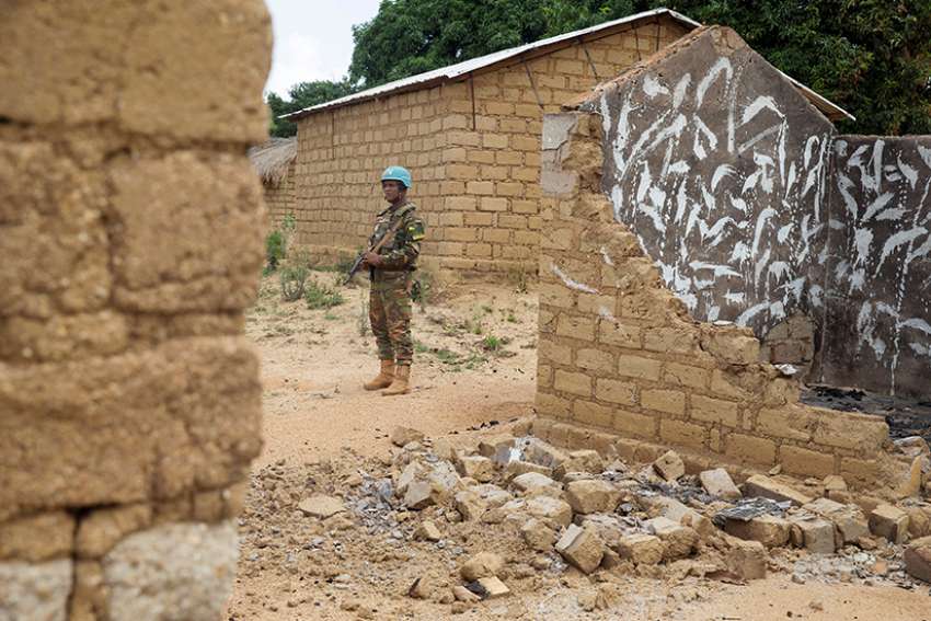 A Bangladeshi United Nations peacekeeping soldier stands amid homes destroyed by violence in 2017 in the abandoned village of Yade, Central African Republic. Bishops in the Central African Republic have declared two days of mourning for victims of recent massacres. 