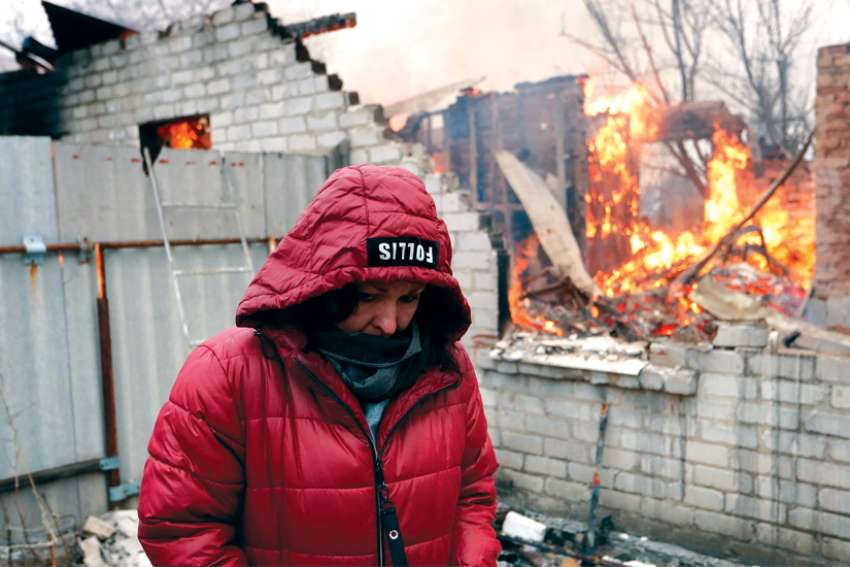 A local resident stands next to her house that caught fire after recent shelling in the separatist-controlled city of Donetsk, Ukraine, Feb. 28.