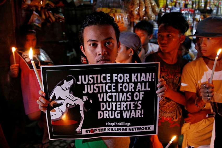 A young man in Manila, Philippines, holds a placard Aug. 25 at a memorial for Kian Delos Santos, a 17-year-old shot in an escalation of Philippine President Rodrigo Duterte&#039;s war on drugs.