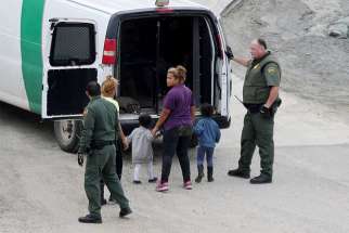 U.S. Customs and Border Protection officials Dec. 9 detain a migrant woman and children after they crossed illegally with other migrants in the U.S. from Mexico at International Friendship Park in San Diego. They were part of a caravan of thousands from Central America trying to reach the United States. 