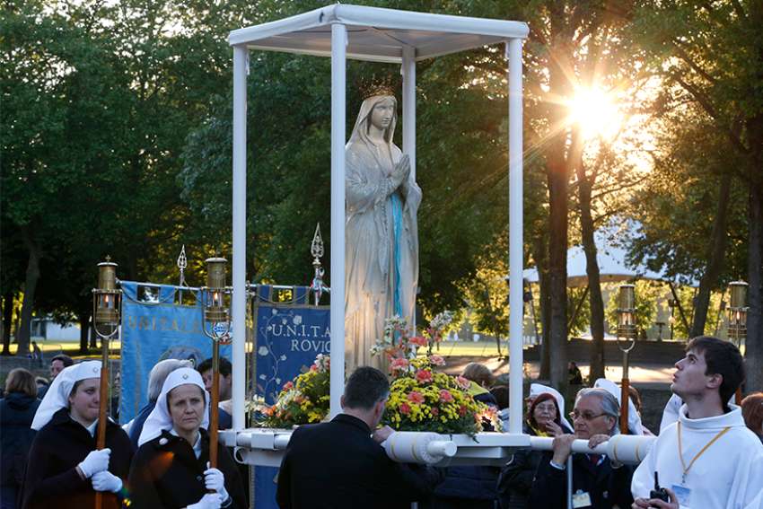 Attendants prepare to carry a statue of Mary in procession at the Shrine of Our Lady of Lourdes in southwestern France May 16, 2014. In Nov. 29 remarks, Pope Francis encouraged rectors and workers at shrines to make guests feel &quot;at home.&quot;