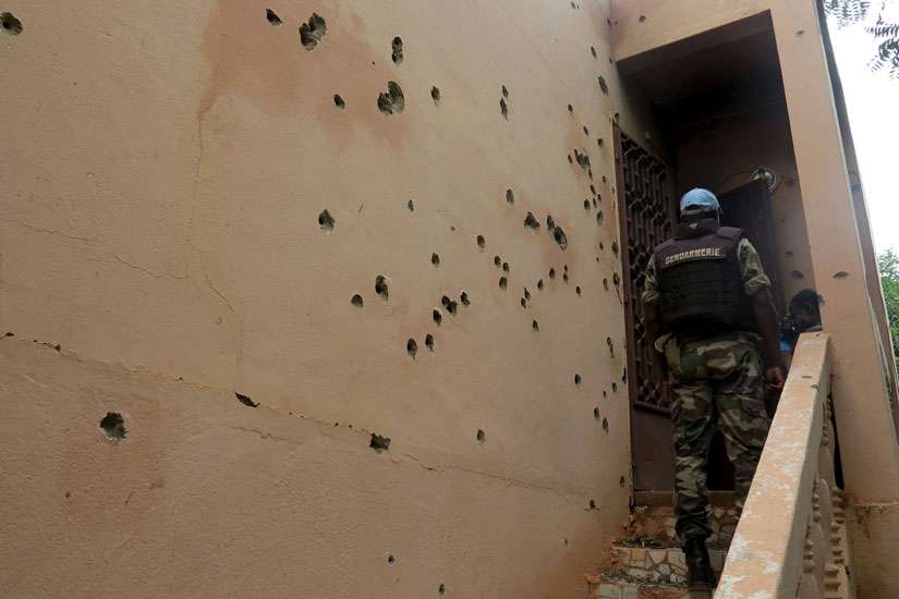 An armed police officer climbs stairs at the hotel where 17 people died in Sevare, Mali, Aug. 11.