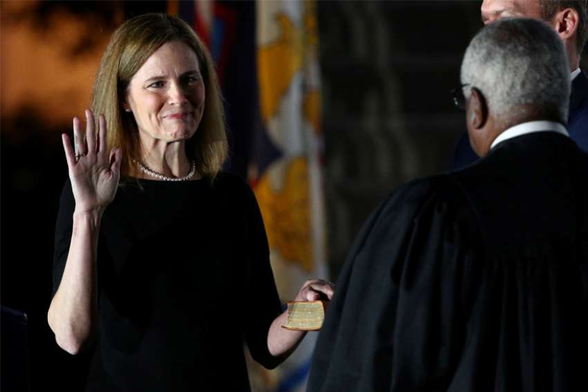 Judge Amy Coney Barrett holds her hand on the Bible as she is sworn in as an associate justice of the U.S. Supreme Court by Supreme Court Justice Clarence Thomas at the White House in Washington Oct. 26, 2020.