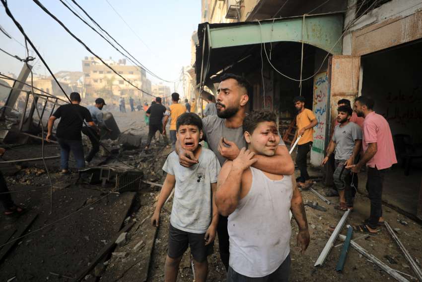 A man embraces Palestinian children as people search for casualties at the site of an Israeli airstrike on a residential building in Gaza City.