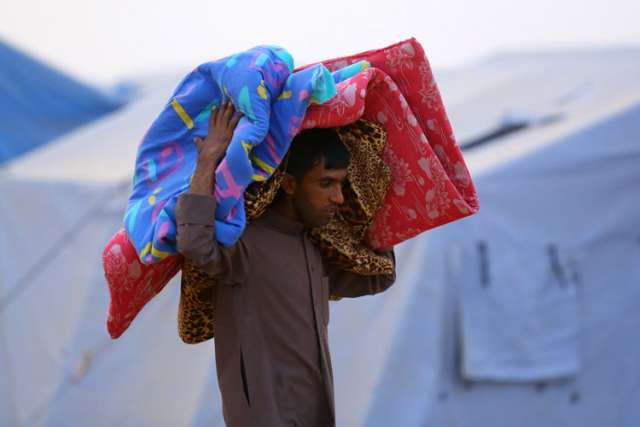 An Iraqi refugee carries a mattress at a camp near the northern city of Irbil June 12. Hundreds of thousands of people who have fled their homes in Mosul are left without access to aid, officials said
