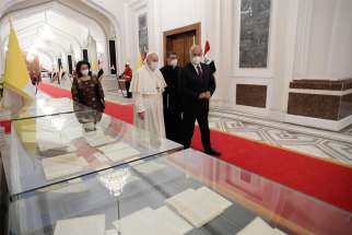 Pope Francis and Iraqi President Barham Salih walk inside the presidential palace in Baghdad March 5, 2021.
