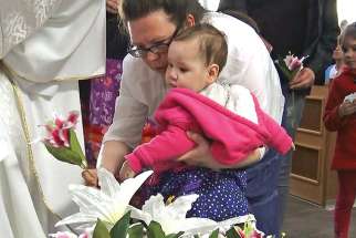 Lily Hunter, with her daughter Kateri, who was named in honour of the Indigenous saint, lays flowers in the Cathedral in St. Paul. St. Kateri was canonized in 2012.