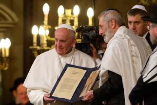 Pope Francis and Rabbi Riccardo Di Segni, the chief rabbi of Rome, hold a codex containing five pages of Jewish biblical commentary during the pope&#039;s visit to the main synagogue in Rome Jan. 17, 2016.