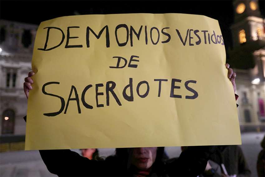  A woman holds a banner that reads &quot;Devils Dressed as Priests&quot; during an Aug. 20 vigil to protest against sexual abuse in the Chilean Catholic church outside the Santiago cathedral. 