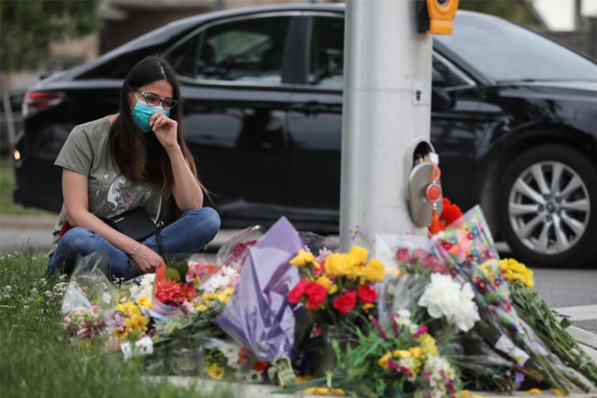A woman wearing a protective mask mourns near a makeshift memorial in London, Ontario, June 7, 2021, following a fatal attack. Canadian Prime Minister Justin Trudeau called the June 6 killing of the family members, who were mowed down by a pickup truck, &quot;a terrorist attack.&quot;