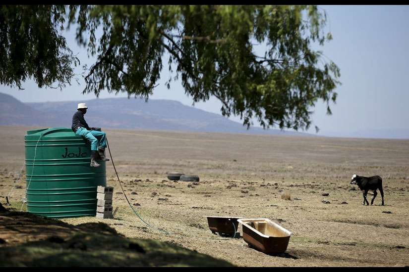 A farmworker sits on a water tank Nov. 9 as he supplies his livestock with water at a drought-stricken farm outside Utrecht, South Africa
