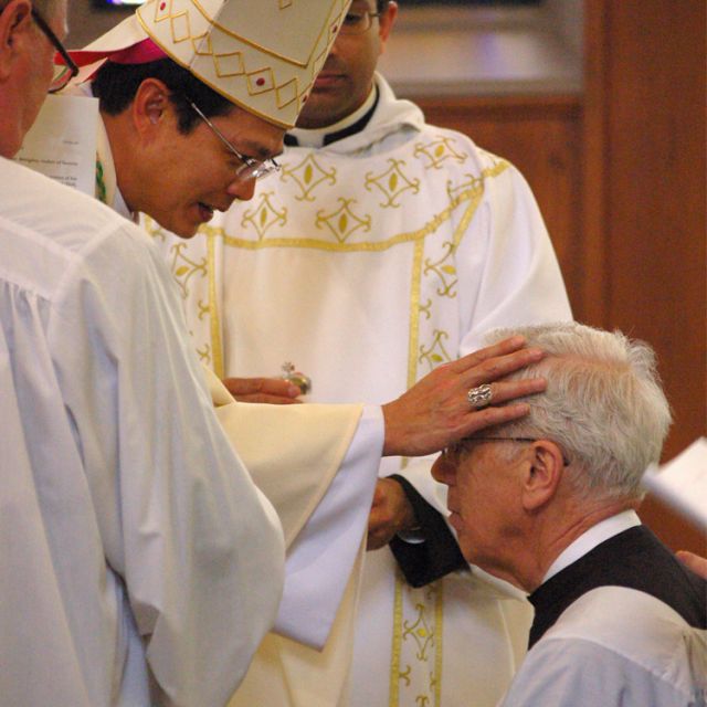 Bishop Vincent Nguyen smiles down upon Aurthur Bousfield after receiving him into the Catholic Church.