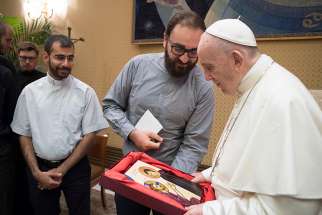 Pope Francis accepts a religious icon during an audience with European Jesuits in formation at the Vatican Aug. 1.