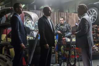 Brian (Paul Walker) and Dom (Vin Diesel) meet with a high-level government operative (Kurt Russel) in Furious 7. 