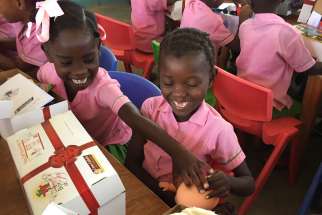 Children in Les Cayes, Haiti, open presents March 22 that they received through the Box of Joy program of Cross Catholic Outreach, a Florida based relief and development agency. 