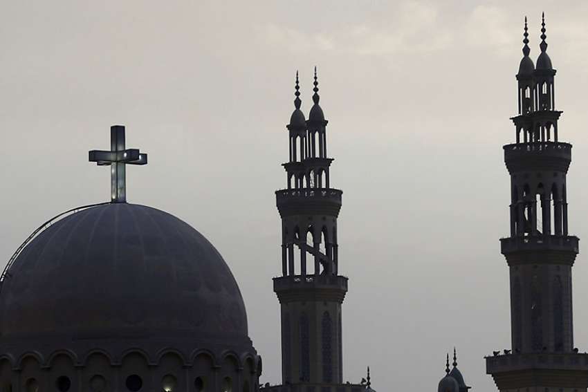 A cross above a church is seen alongside minarets of a mosque April 17 in Cairo ahead of Pope Francis&#039; April 28-29 visit.