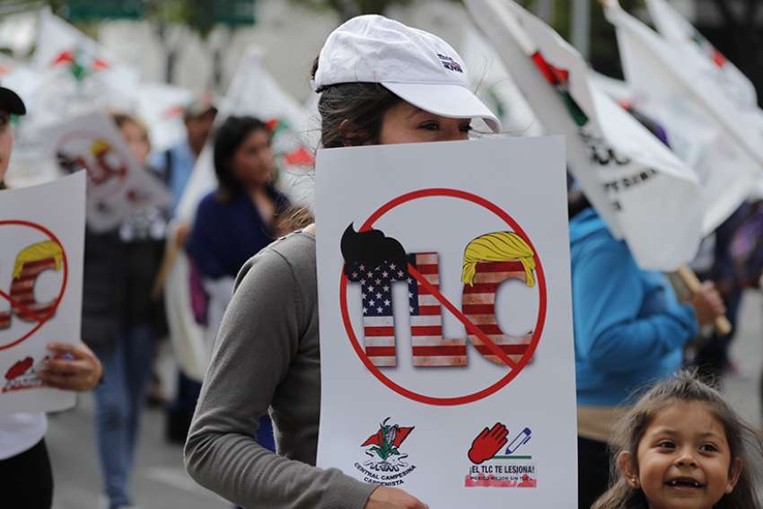 A woman holds a banner against a free trade agreement during a demonstration in late August to protest the start of the North American Free Trade Agreement renegotiations talks in Mexico City. Mexican and American bishops called on negotiators working to overhaul a 23-year-old trade agreement to ensure that any changes keep the needs of poor people foremost.