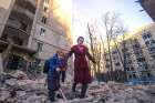 A woman with a child evacuates from a residential building damaged by Russian shelling in Kyiv, Ukraine, March 16, 2022.
