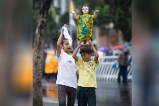A boy carries a Santo Nino statue in Manila, Philippines, prior to the closing Mass in Rizal Park Jan. 18.