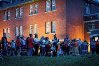 Kamloops residents and First Nations people gather to listen to drummers and singers at a memorial in front of the former Kamloops Indian Residential School in British Columbia.