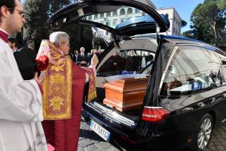 A priest blesses the coffin of Australian Cardinal George Pell upon its arrival for a funeral Mass in St. Peter’s Basilica at the Vatican Jan. 14.