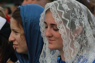A young woman prays during the opening Mass for World Youth Day at Blonia Park in Krakow, Poland. 