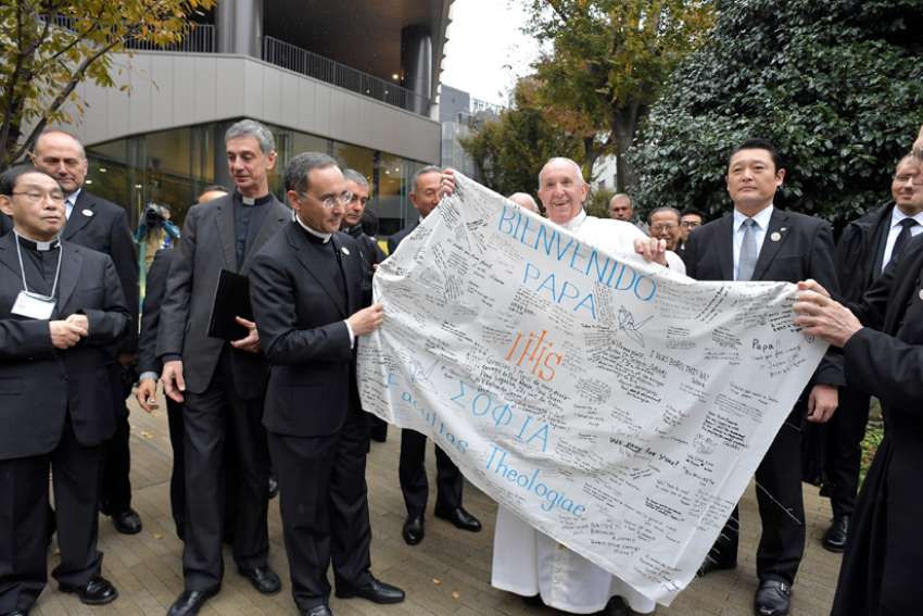 Pope Francis receives a welcome banner from the theology faculty at Jesuit-run Sophia University in Tokyo Nov. 26, 2019.