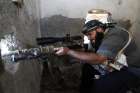 A Free Syrian Army fighter aims his weapon through a hole in a wall from inside a room in Raqqa Sept. 11.