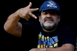 Former Argentine soccer player Diego Maradona gestures from a balcony as he attends the Argentine First Division soccer match between Boca Juniors and Quilmes at La Bombonera stadium in Buenos Aires on July 18, 2015.