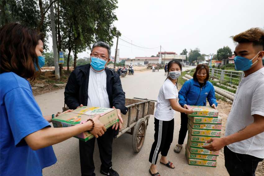 Father Francis Xavier Nguyen Duc Dai distributes food to local people while wearing a protective mask in Son Loi, Vietnam, Feb. 25, 2020. The area has been quarantined due to the coronavirus.