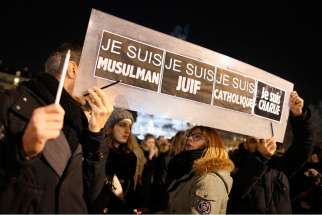 People hold a placard that reads &quot;I am Muslim, I am Jewish, I am Catholic, I am Charlie&quot; during a Jan. 8 vigil in Paris, following the mass shooting at the offices of Charlie Hebdo, a satirical newspaper in Paris. Pope Francis condemned the killings of a t least 12 people at the offices of the publication Jan. 7 and denounced all &quot;physical and moral&quot; obstacles to the peaceful coexistence of nations, religions and cultures.