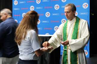 A young woman receives Holy Communion from Fr. Frank Portelli at the Rogers Centre Sunday Mass. 
